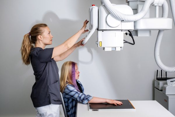 Sairaanhoitaja ottamassa kuvaa nuoren asiakkaan käsivarresta röntgenlaitteella.
